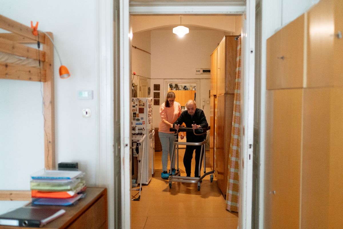 Pflegekraft unterstützt eine ältere Frau bei einem Hausbesuch